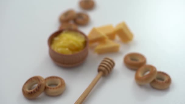 Honey in a wooden bowl, bagels and cheese on a white background — Stock Video