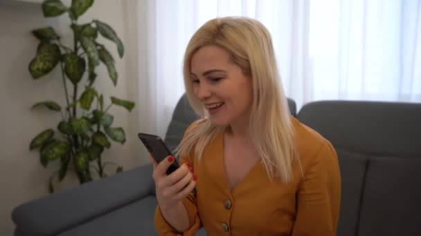 Portret van een gelukkige zakenvrouw geniet van succes op mobiele telefoon op kantoor. Sluiten vrolijke meisje lezen goed nieuws op de telefoon in slow motion. Verrast dame viert overwinning op de telefoon in appartement. — Stockvideo