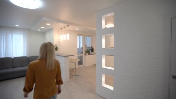 Moving in new apartment, woman with keys walks into her new flat, empty white rooms, new home — Stock Video