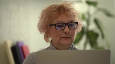 Fotoğraf makinesine bakıp konuşan olgun bir kadın. Büyükannem internetten akrabasıyla sohbet ediyor. Video görüşmesi yapıyor. Orta yaşlı blogcu vlog 'u kaydediyor.