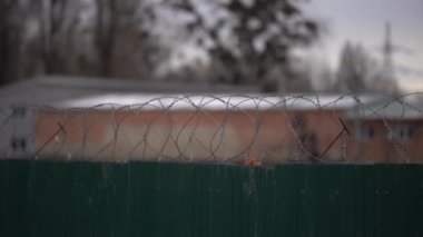 Dikenli telli uzun hapishane duvarları, uzak tel örgüler ve uzaktan gözetleme kulesi görünür.