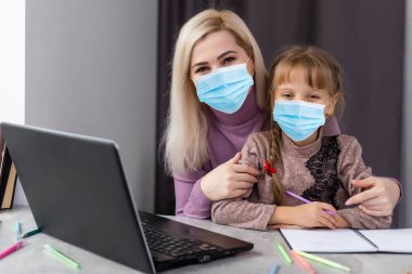Tıp maskeli küçük kız evde ders çalışıyor. Salgın, salgın