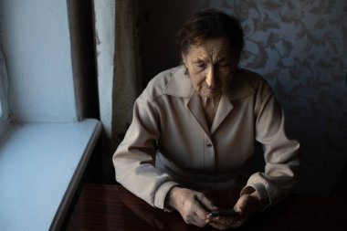 Evde akıllı telefonu olan yaşlı bir kadın.