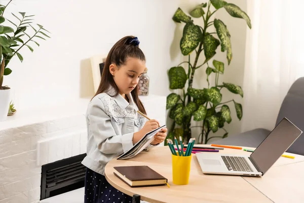 Petite fille faisant ses devoirs à la maison et utilisant un ordinateur portable — Photo
