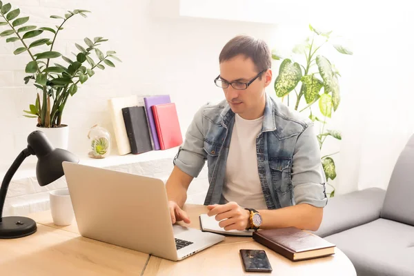 Focused young businessman holding video call with clients on laptop. Concentrated millennial man in glasses giving online educational class lecture, consulting customer.