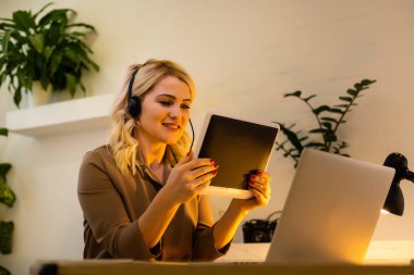 Dijital tablet kullanan gülümseyen genç bir kadın.