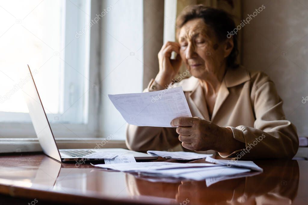 Pensioner read countless papers and is very focused. Senior woman calculating taxes at home. Retired woman calculating her domestic bills. Business, savings, annuity insurance, age and people concept