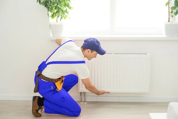 Plumber man is blocking repairs radiators of heating battery in apartment tap