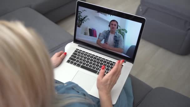Video call. Remote work. A girl work from home. She communicate via video communication with colleagues using computer — Stock Video