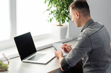 Evden dizüstü bilgisayarda çalışan mutlu genç tasarımcı, serbest konsept.