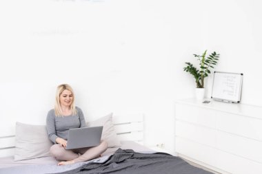 Yatakta laptopunu kullanan güzel bir kadın.