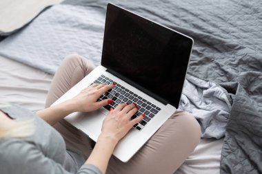 Yatakta laptopunu kullanan güzel bir kadın.