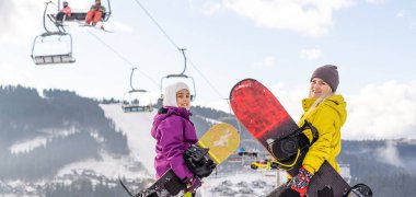 Anne ve kızı kış tatilinde snowboard yapıyor.