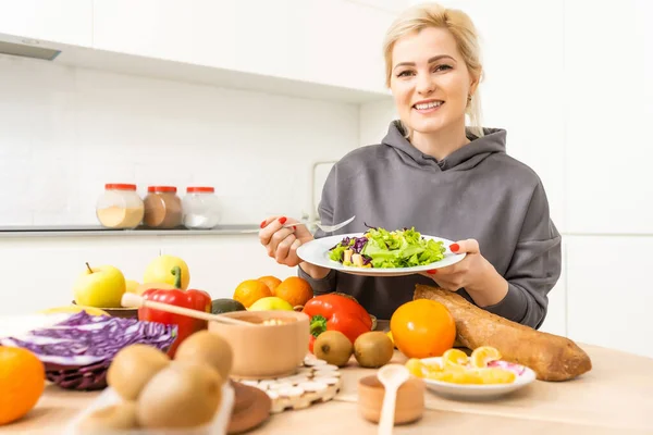 healthy eating, dieting and people concept - close up of young woman eating vegetable salad at home