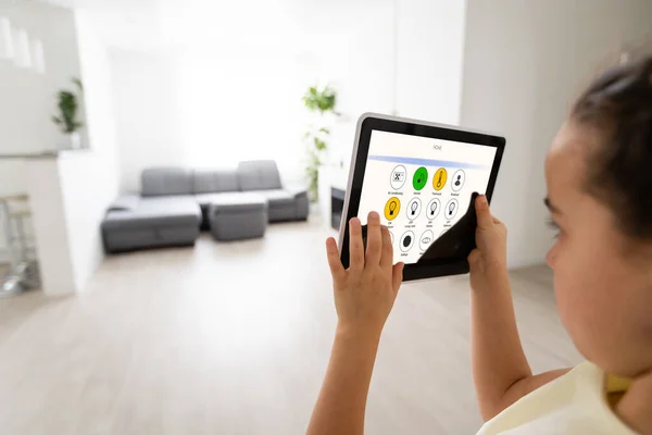 Niña usando tableta con control remoto en casa, sala de estar en el fondo, hogar inteligente — Foto de Stock