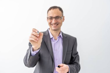 Erkek keçeli kalemle cam tahtaya bir şey yazıyor.