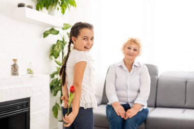 Küçük tatlı bir kız, büyükannesine ışık odasında buket sunuyor.