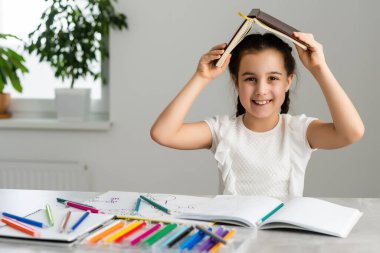 Eğitim ve okul konsepti. Okulda bir sürü kitabı olan gülümseyen küçük kız öğrenci.