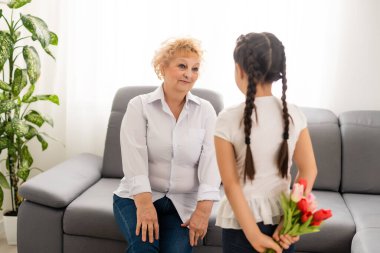 Küçük tatlı bir kız, büyükannesine ışık odasında buket sunuyor.