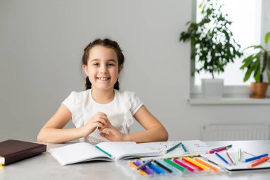 Eğitim ve okul konsepti. Okulda bir sürü kitabı olan gülümseyen küçük kız öğrenci.