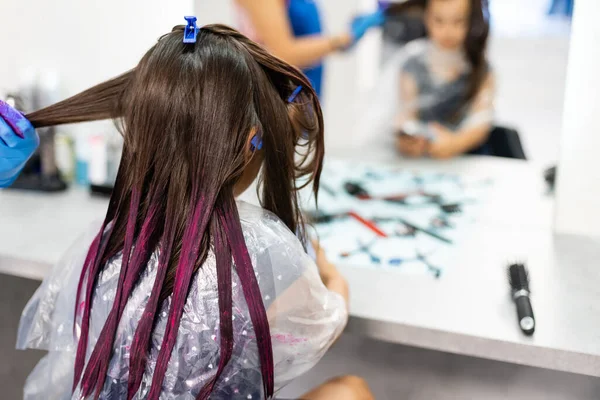 hairdresser dyes hair for a little girl in a hair salon. Dyed, bleached hair