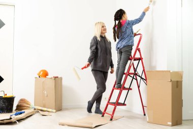 Mutlu güzel bir kadın duvar boyuyor.