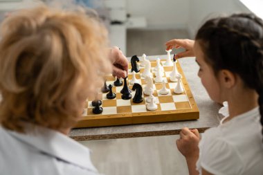 Evde büyükannemle satranç oynayan genç bir kız.