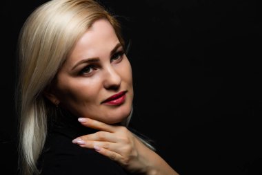 Siyah arka planda uzun sarı saçlı güzel bir mankenin yakın plan portresi.