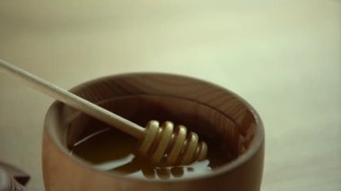 Bal damlıyor, ahşap kaseye bal damlatıyor. Yakın plan. Ahşap bal kaşığından batırılan sağlıklı organik bal, yakın plan. 4K UHD video görüntüleri. Yavaş çekim