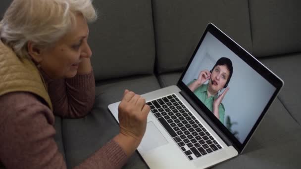 Ältere Frau telefoniert am Laptop, winkt dem Bildschirm zu, chattet mit Kindern, freier Platz — Stockvideo