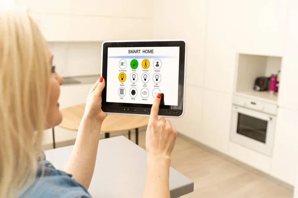 Intelligent home concept. Young woman using smart home application on a tablet — Stock Photo, Image
