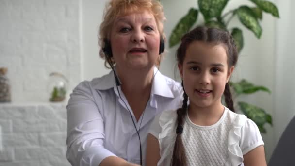 Mała dziewczynka i babcia w słuchawkach w domu — Wideo stockowe