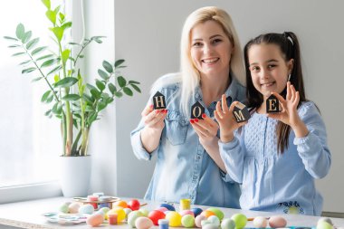 Anne ve kızı yumurtaları renklerle boyarlar. Eğlenmene bak. Mutlu aile Paskalya için hazırlanıyor, yazıtları evde tutun..