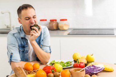 Mutlu genç adam romantik bir akşam yemeği hazırlıyor sebze tarifleri diyet menüsünü arıyor, gülümseyen koca sağlıklı vegan yemekleri pişiriyor mutfak içinde salata pişiriyor.