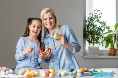 Çekici genç bir kadın ve küçük tatlı bir kız Paskalya kutlaması için hazırlanıyorlar. Anne ve kızı Paskalya 'dan önce yumurta boyarken birlikte vakit geçiriyorlar..