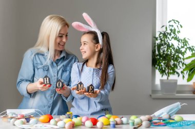 Anne ve kızı yumurtaları renklerle boyarlar. Eğlenmene bak. Mutlu aile Paskalya için hazırlanıyor, yazıtları evde tutun..