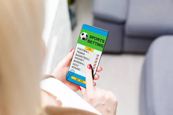 Woman holding a mobile phone with sports betting website in the screen. — Stock Photo, Image