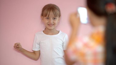 İki küçük kız bir akıllı telefonla fotoğraf çekiyor.