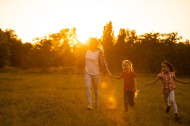 Anneler ve kızları gün batımında bir tarlada uçurtmayla