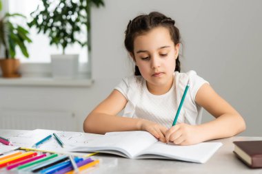 Sevimli küçük kız evde çalışıyor ve gülümsüyor.