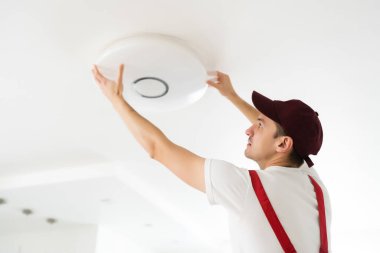 Elektrikçi tavana bir avize yerleştirir. İnşaat konsepti