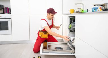 Bulaşık makinelerinin tamiri. Usta eve geldi ve bulaşık makinesini tamir ediyor.