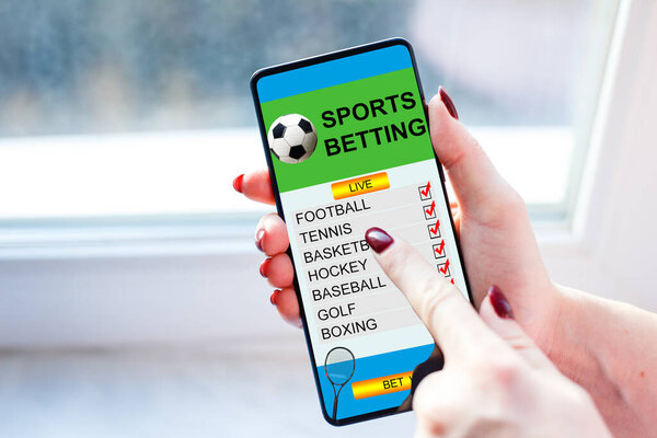 woman holding a mobile phone with sports betting website in the screen.