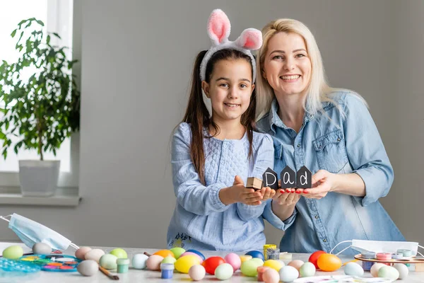 Anne ve kızı yumurtaları renklerle boyarlar. Eğlenmene bak. Mutlu aile Paskalya için hazırlanıyor..