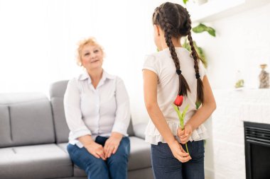 Torunu olan mutlu bir büyükanne. Evde çiçekli kadın ve çocuk