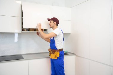 Genç adam mutfak mobilyalarını monte ediyor..