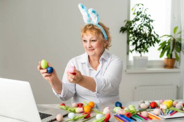 Yaşlı kadın Paskalya yumurtası sarısı renginde acı çekiyor. Aile Paskalya için hazırlanıyor. Yumurtayla yakın çekim eller.