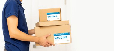 COVID-19 pandemik tecrit konsepti sırasında temassız teslimat. Maske ve eldiven takan teslimatçı tıbbi ekipmanlarla dolu bir paket tutuyor.