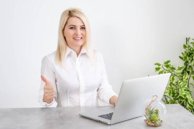 Ofisinde dizüstü bilgisayarıyla çalışan güzel genç bir kadın..