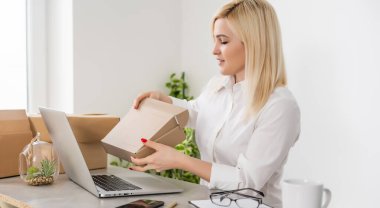 Müşteri için paket zarfları hazırlayan genç bir kadın.